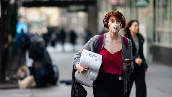 A woman wearing a mask in New York City. Financial experts believe that the virus-suppression effect of wearing face masks helps to preserve economic activity. 