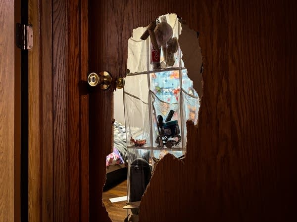A large hole in a bedroom door
