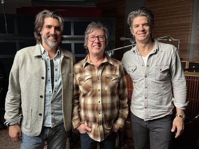 Three men stand together for a group photo