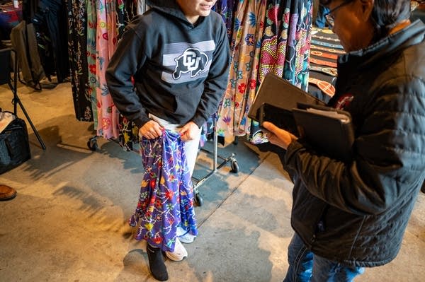 A customer holds a skirt up with one leg through the article of clothing.