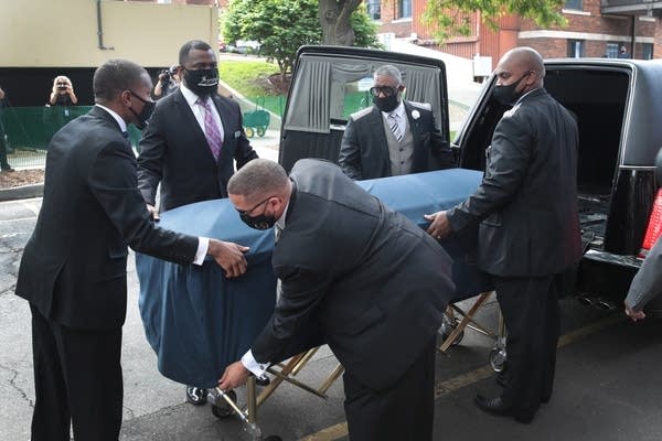 People bringing in a casket. 