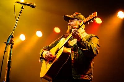 A musician plays guitar onstage in a music venue