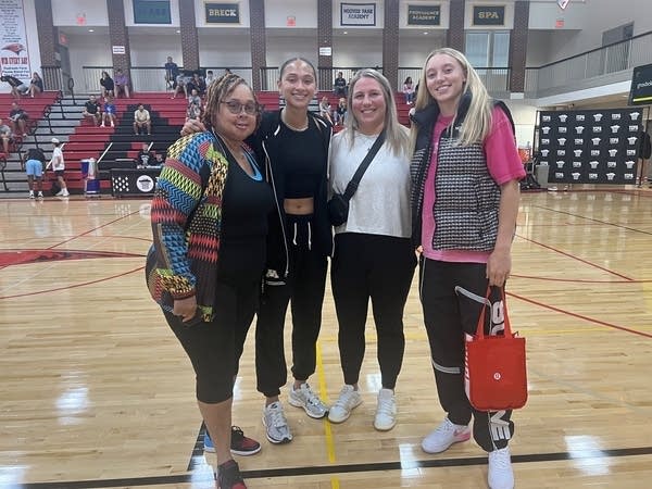 Four women pose for a photo on a basketball court