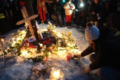 A person kneels and places a candle