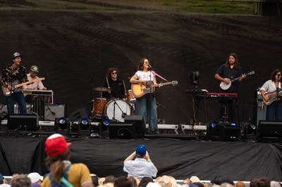 Waxahatchee's Katie Crutchfield sings into a microphone and strums a guitar.