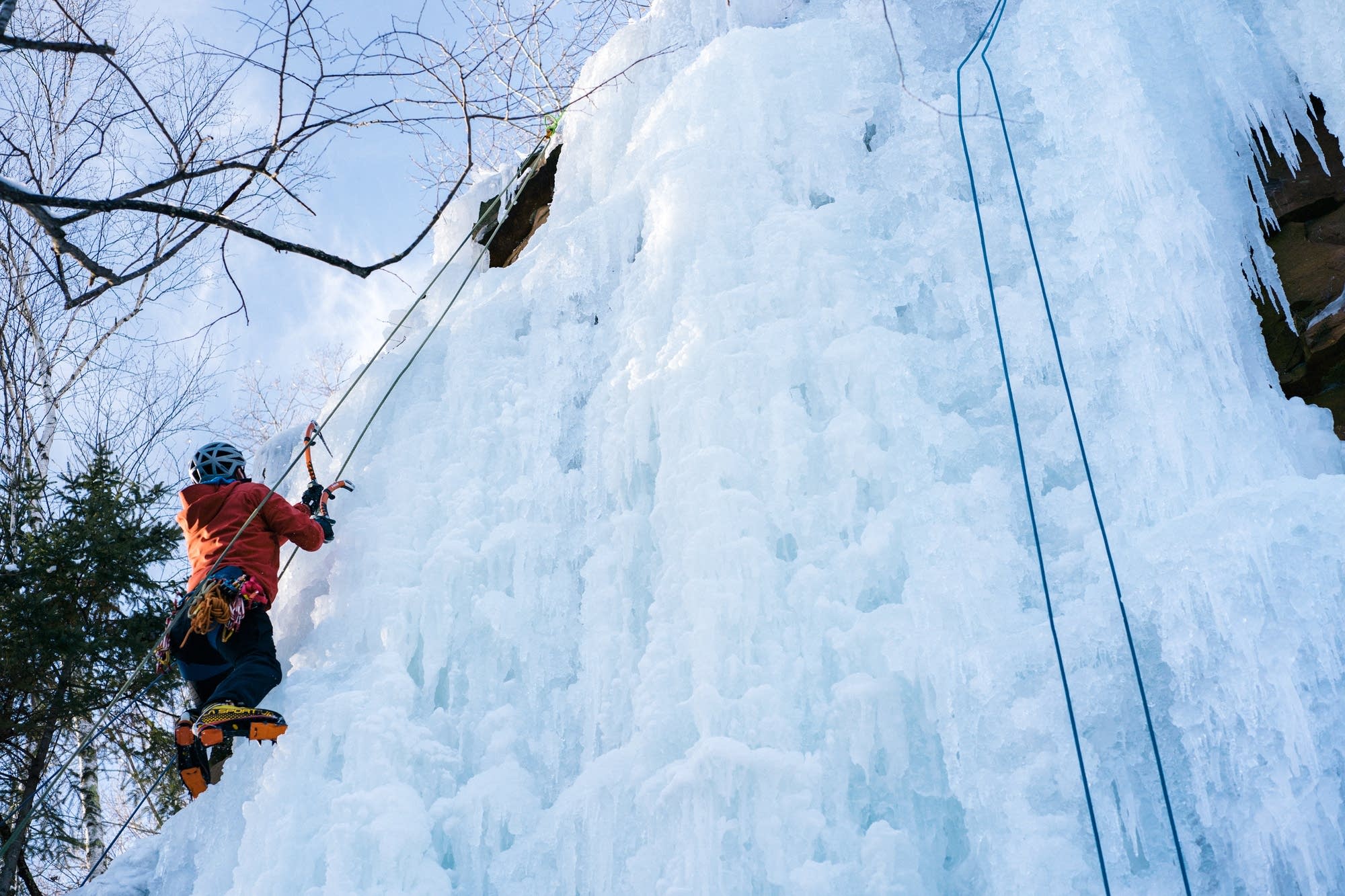 A climber scales a wall of ice.