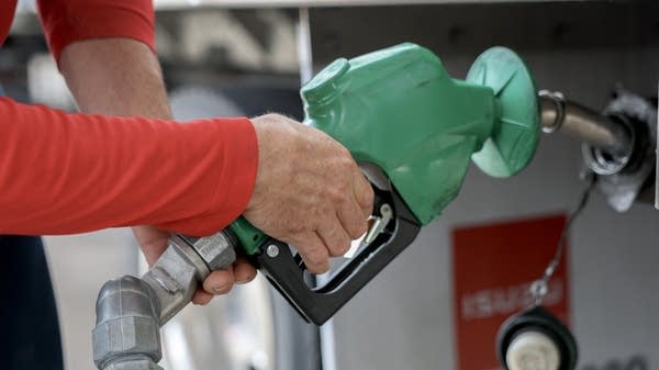 Man pumping diesel fuel, illustrating rising diesel price impact on transport