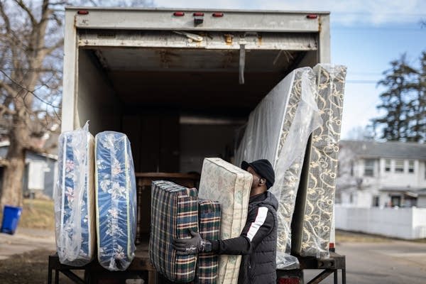 A person unlaods cushions from a box truck