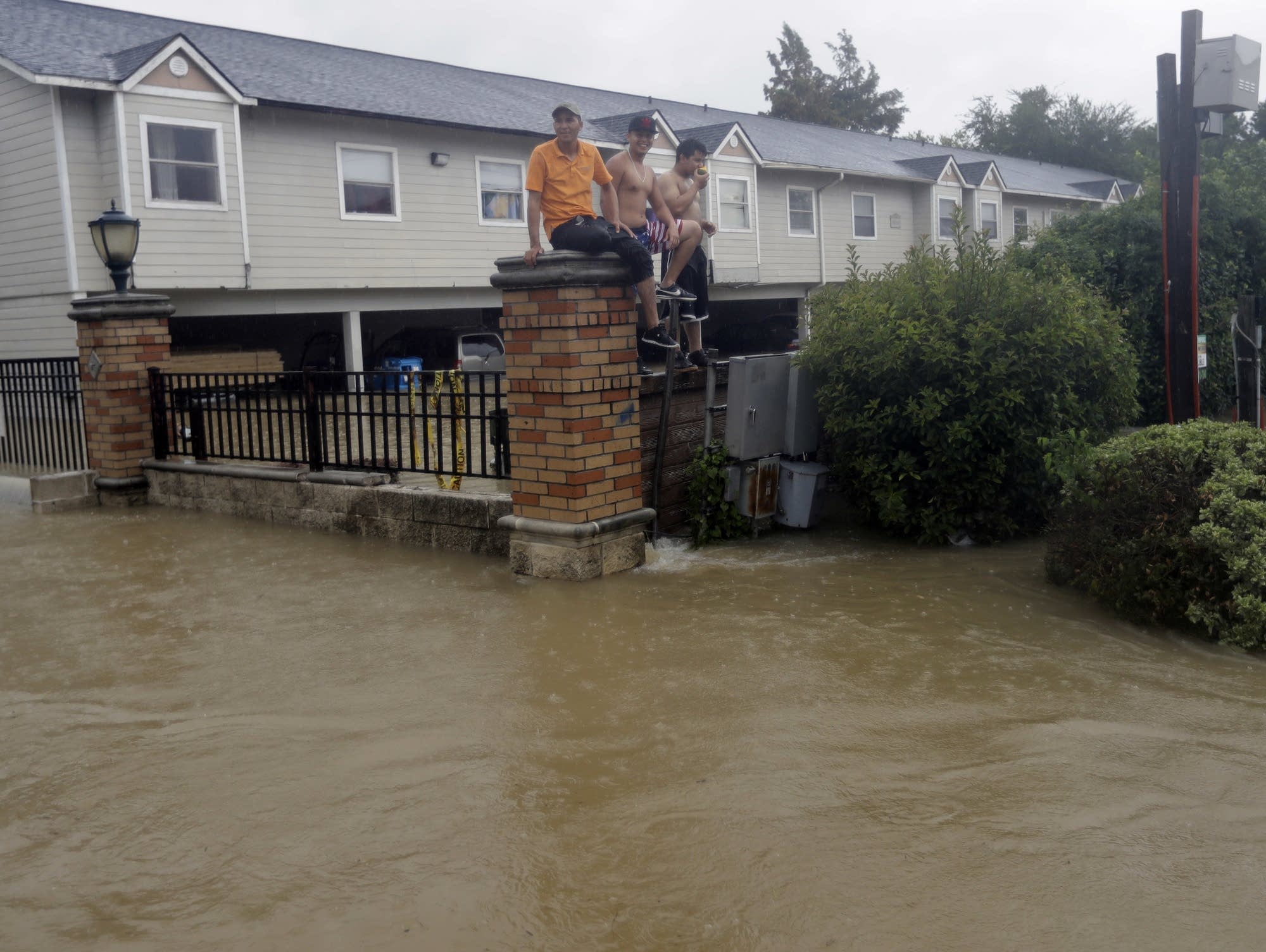 Residents sit on a fence surrounded by floodwaters