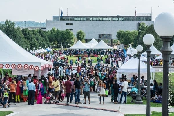 Crowds of people gather in and around tents at a festival