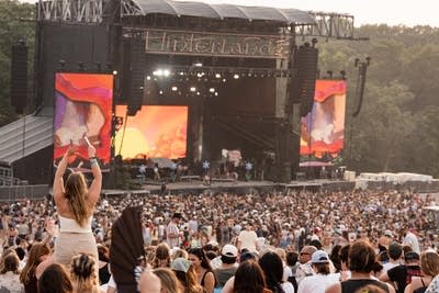 Throngs of music fans watching a band performing on a large outdoor stage