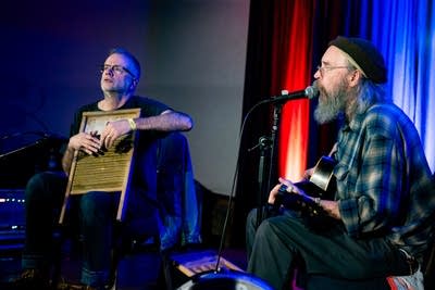 2 men performing folk music on stage
