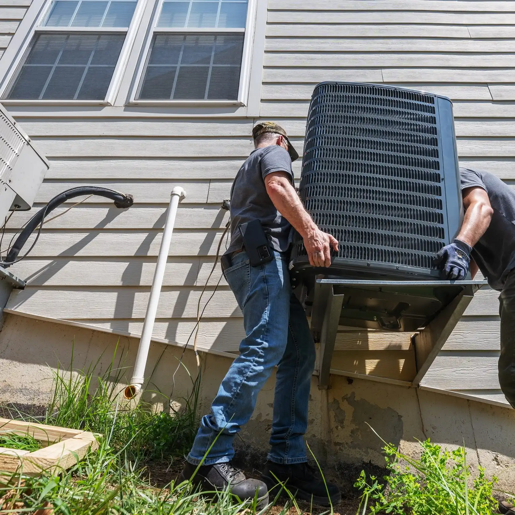 HVAC technicians installing a residential outdoor heating and cooling unit
