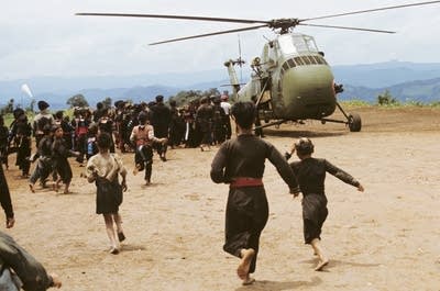 A crowd of people run toward a military airplane.