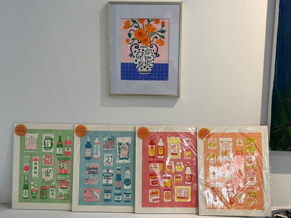Five pictures are seen against a wall, one hangs from the wall in a frame.