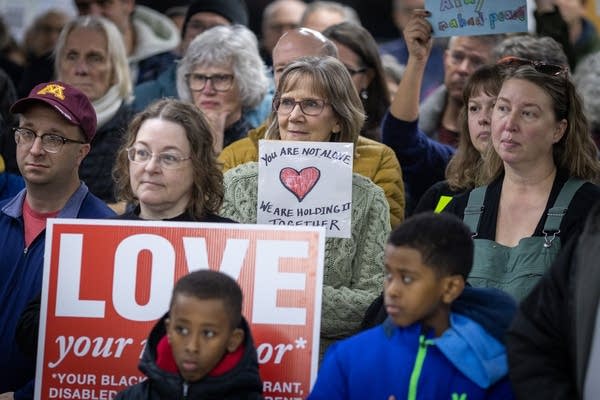 People hold signs at a press conference