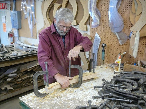 A man tightens clamps on two pieces of wood being laminated