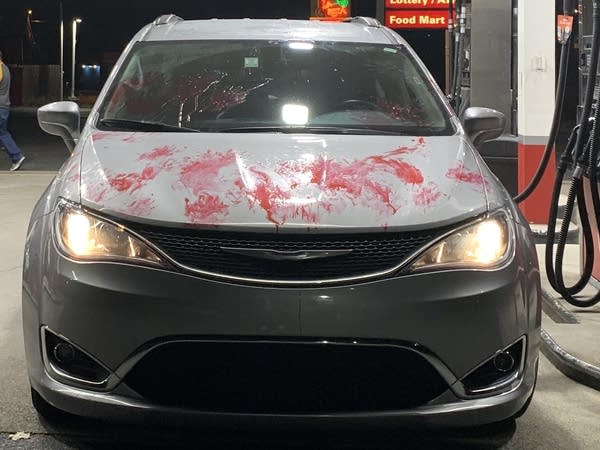 Front view of a minivan covered in fake blood parked at gas station