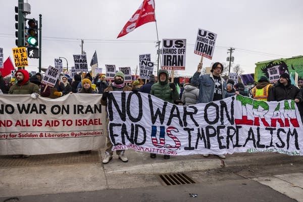 Demonstrators at the front of a protest march hold banners reading "No war on Iran, End U.S. Imperialism."