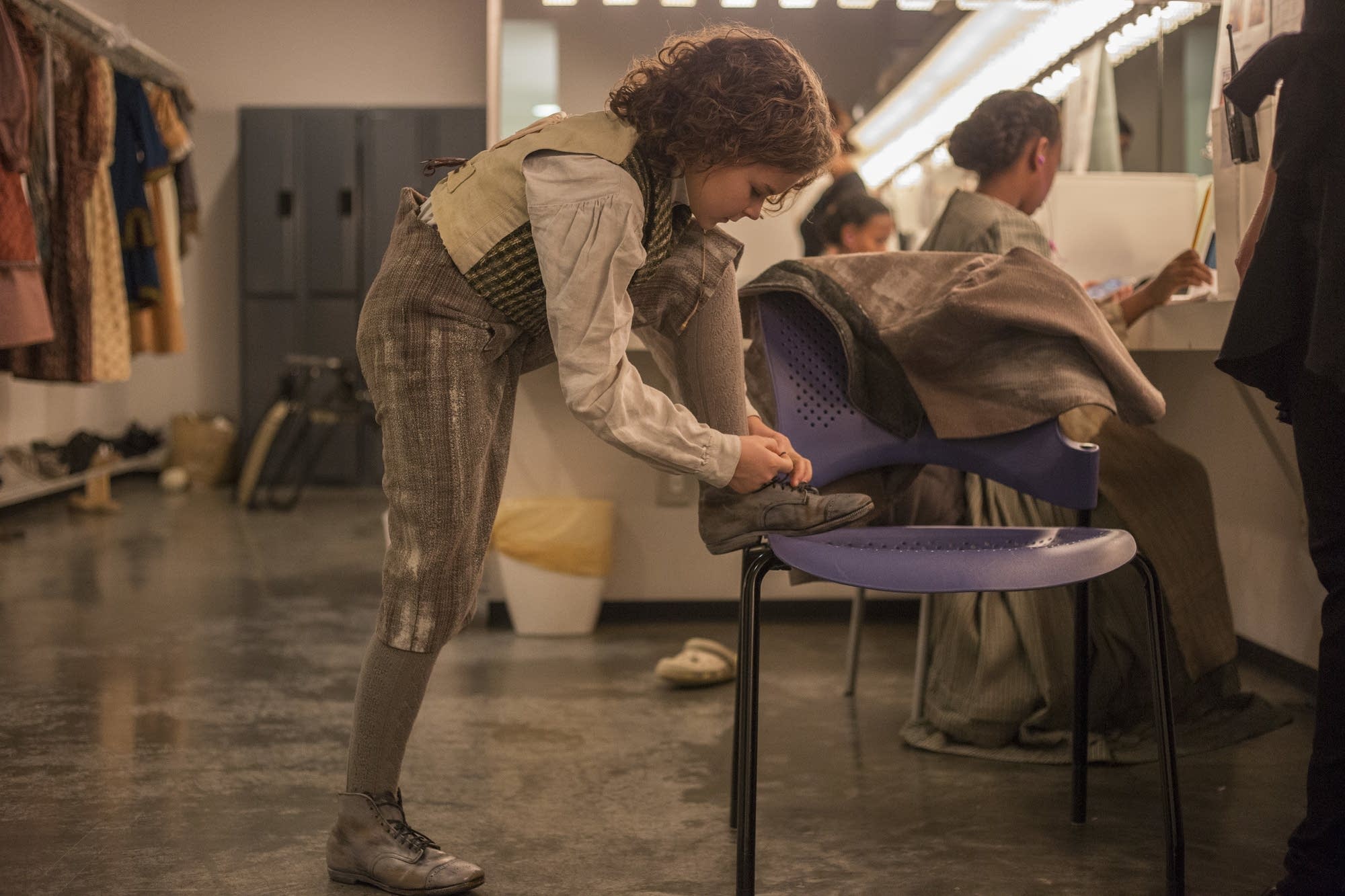 Sophie Jones ties the shoe of her costume before heading to makeup.