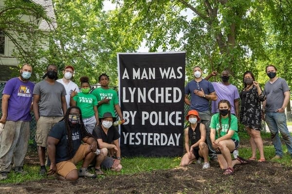 People stand around a sign for a photo.