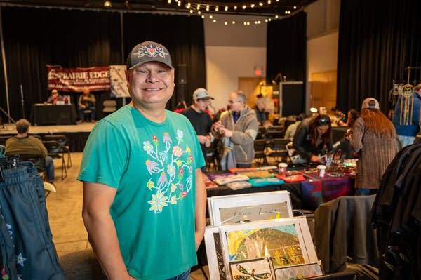 A man poses next to a business booth.