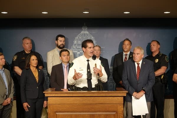 Person stands at podium surrounded by people01