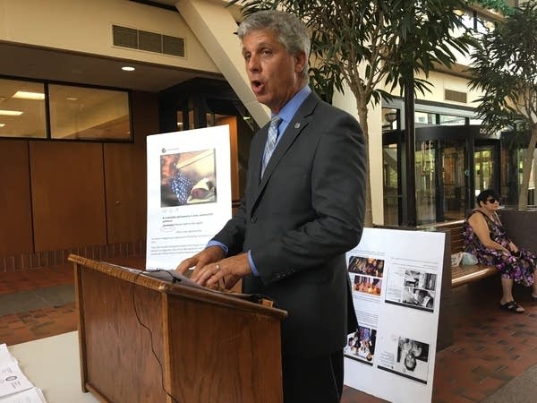 A man speaking at a podium with pictures behind him