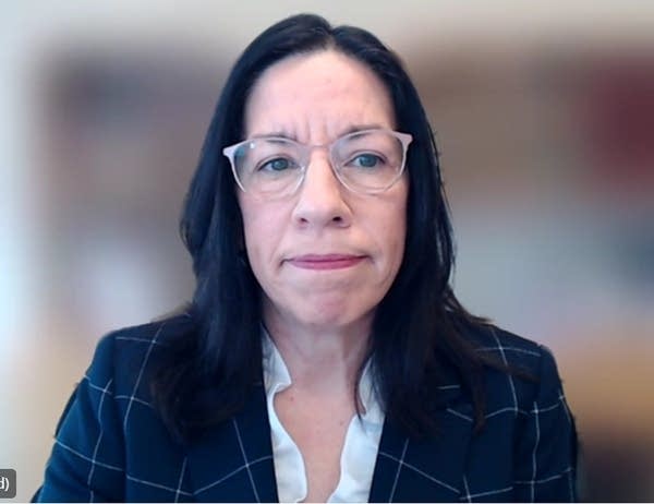 woman in glasses and suit speaks in Teams meeting