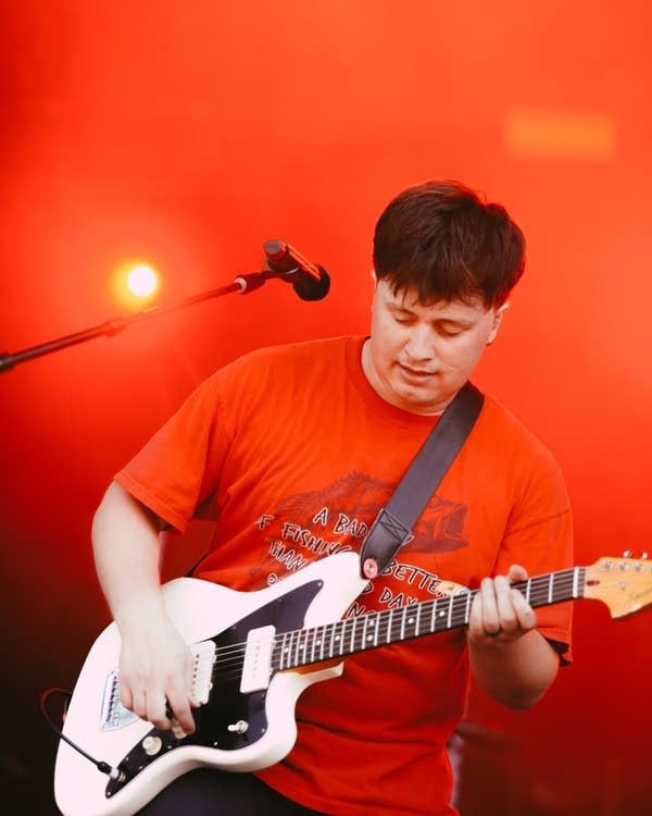 A musician plays guitar on a large outdoor stage