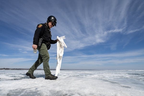 A man walks on ice holding litter