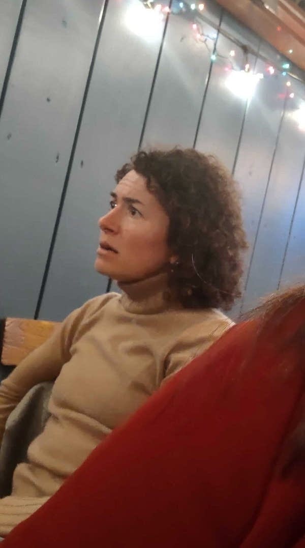 A woman sits and listens to a conversation.