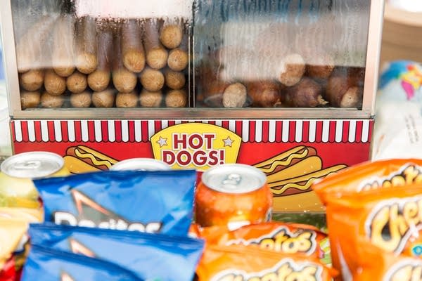 Hot dogs and bratwursts sit in a steamer on the counter.