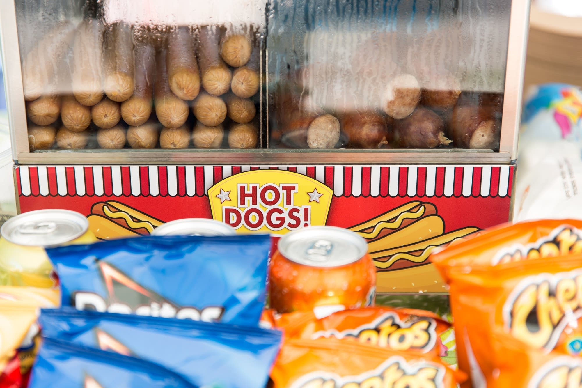 Hot dogs and bratwursts sit in a steamer on the counter.