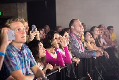 Music fans listen, cheer and snap photos during a concert