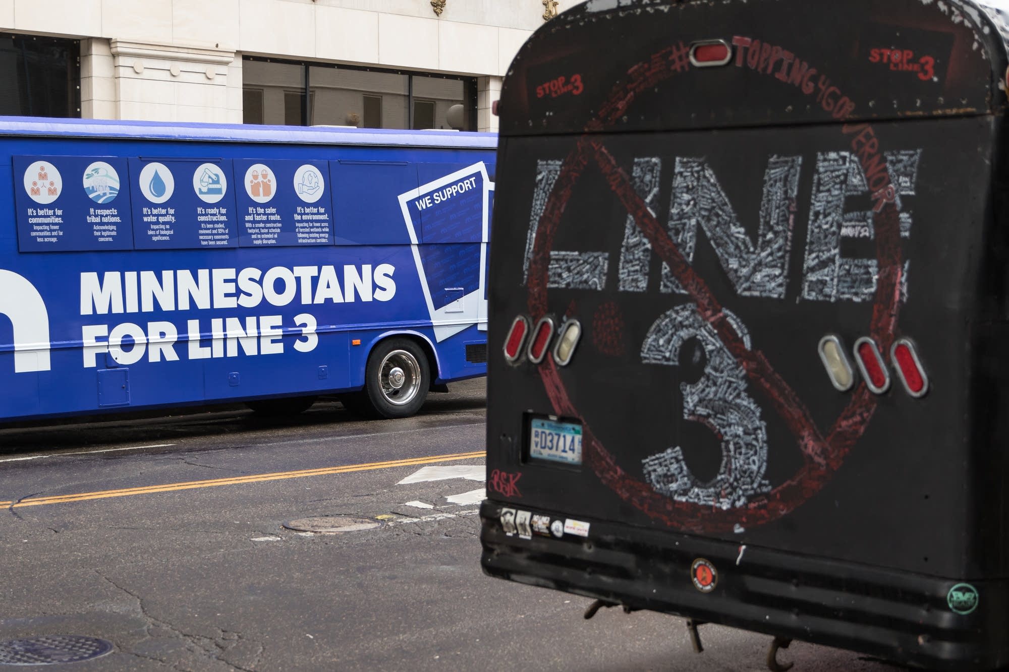 Line three proponents and opponents' buses sit across the street.