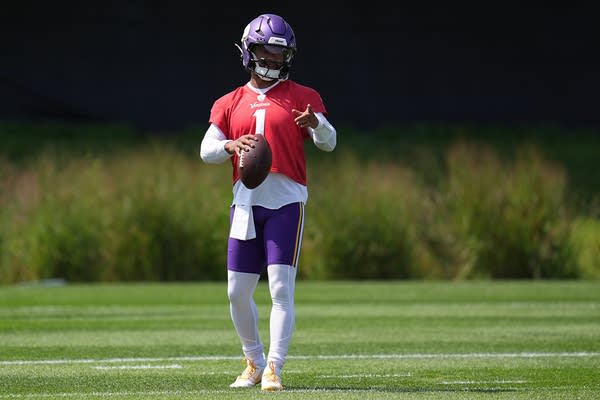 Kyler Murray stands on the field in a red jersey