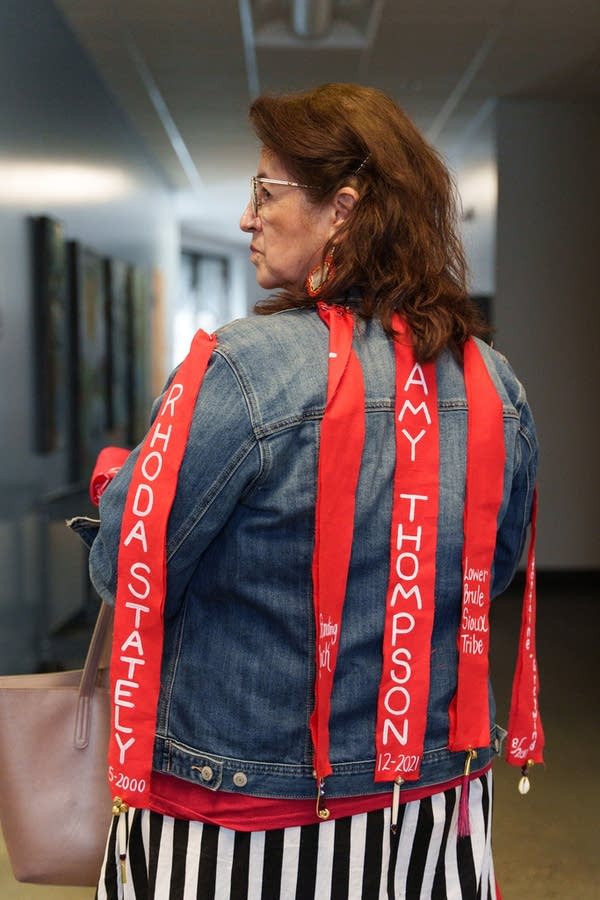 The back of a womans jean jacket with red pieces of fabric