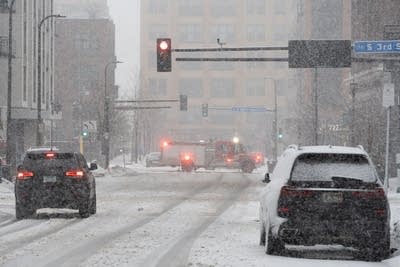 A firetruck drives through downtown Minneapolis during a snowstorm.