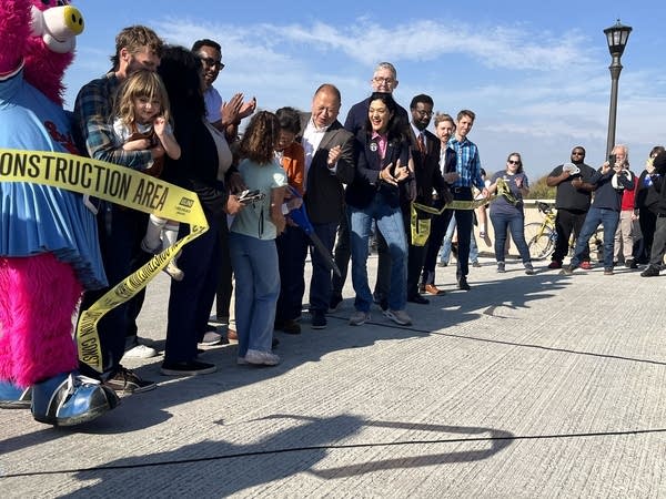 A group claps as a ribbon is cut.