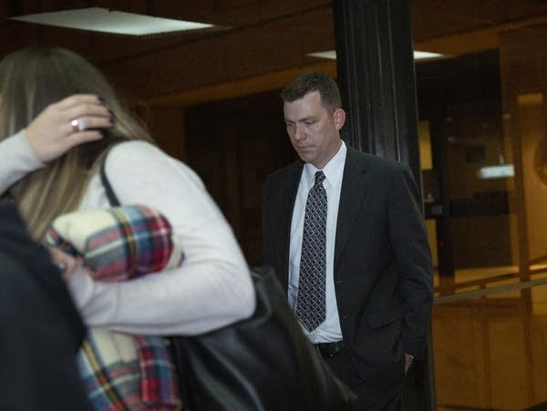 A man is flanked by two women as they walk in a skyway.