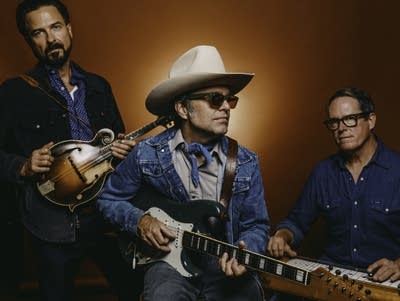 Three men with instruments pose for a portrait