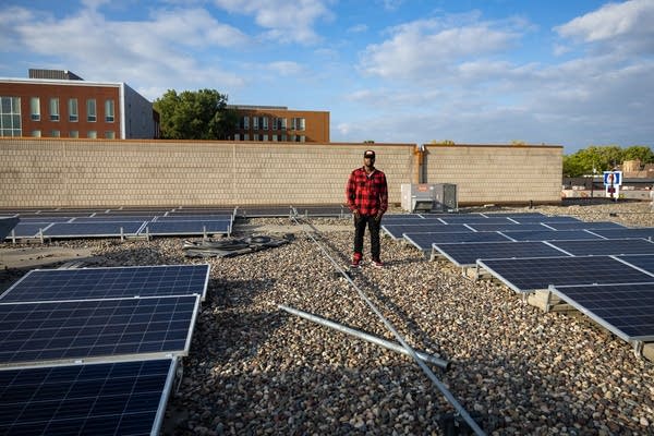 A man stands among solar panels on a roof