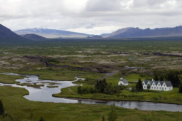 A view of a river winding through a verdant valley with mountains distant