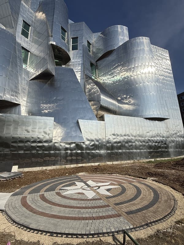 A paving outside the museum with unique angles and shiny metal sides.