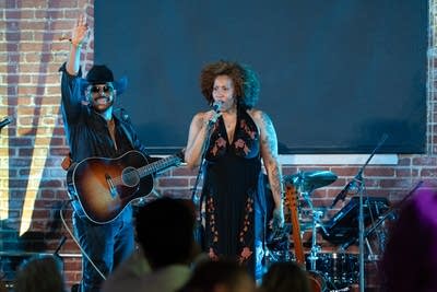 A woman sings into a microphone onstage