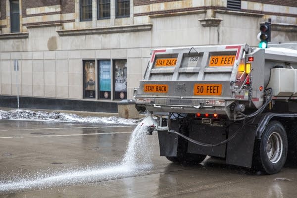 A snow plow lays down road salt in downtown St. Paul, Minn.