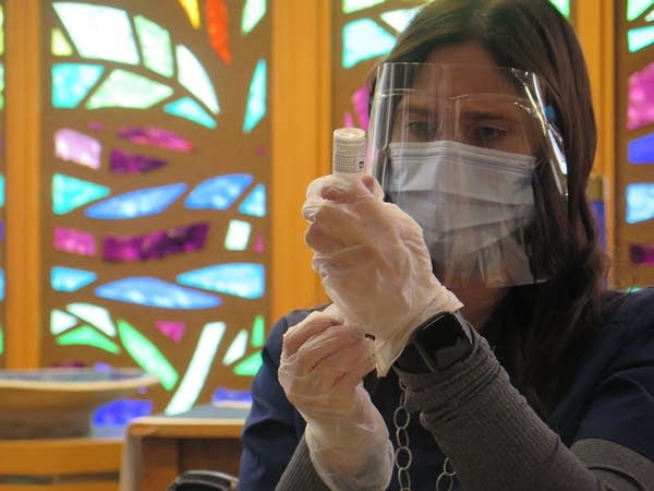 A woman draw a liquid vaccine into a hypodermic needle