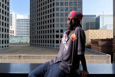 A man sits on a balcony overlooking a cityscape with skyscrapers