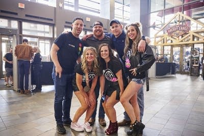 Six friends stand together for a portrait inside an arena